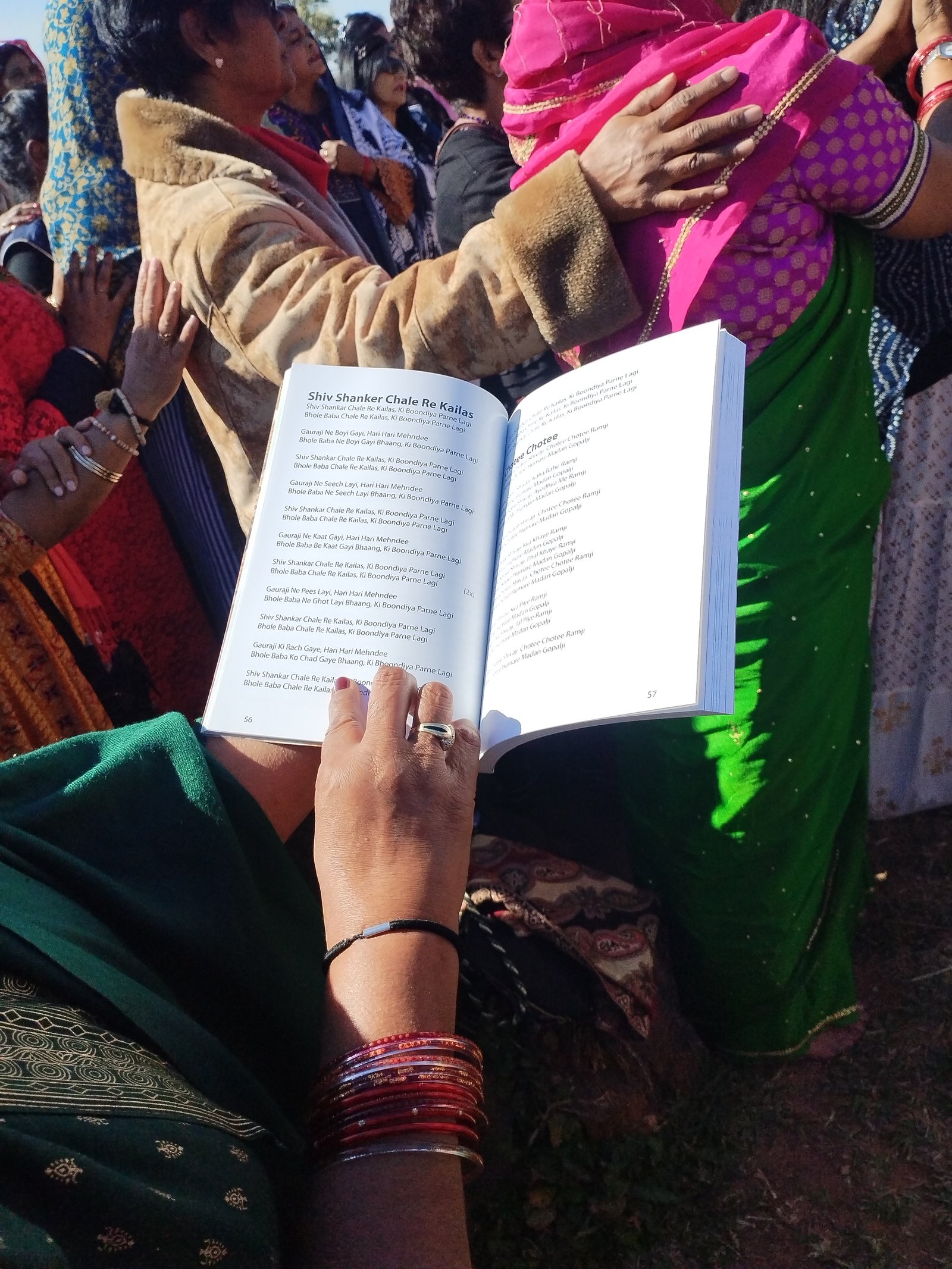 Devotees holding a bhajan book, singing Shiv Shankar Chale Re Kailas