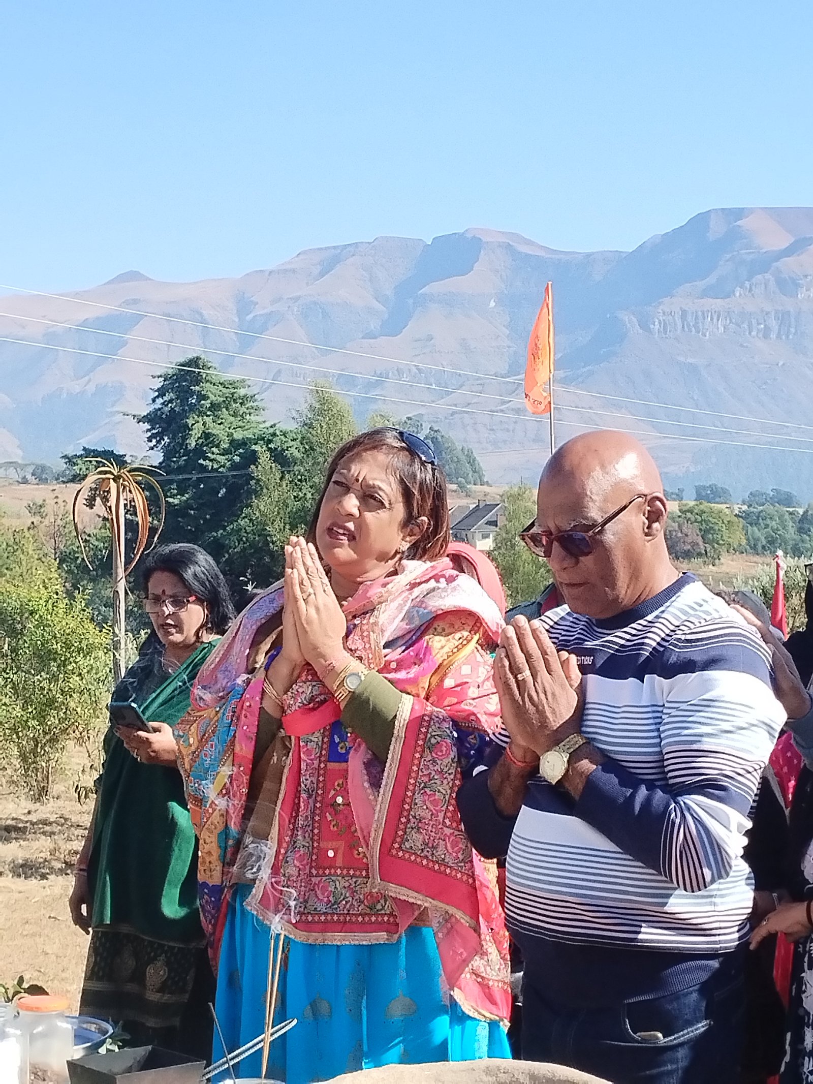 Devotees in prayer with mountains and prayer flag behind