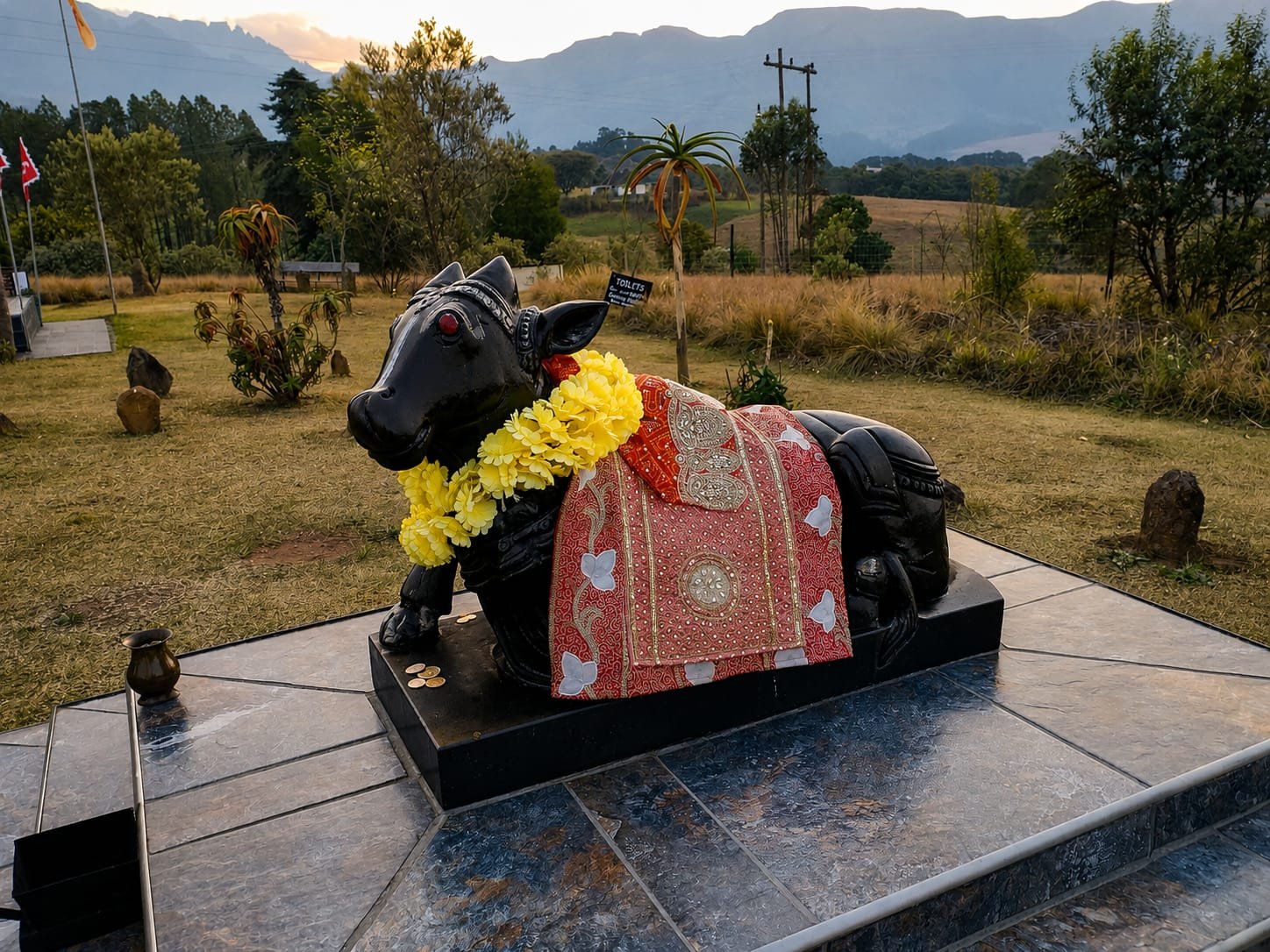 Nandi statue at Shiva Kshetra dressed in ceremonial cloth with the Drakensberg mountains behind